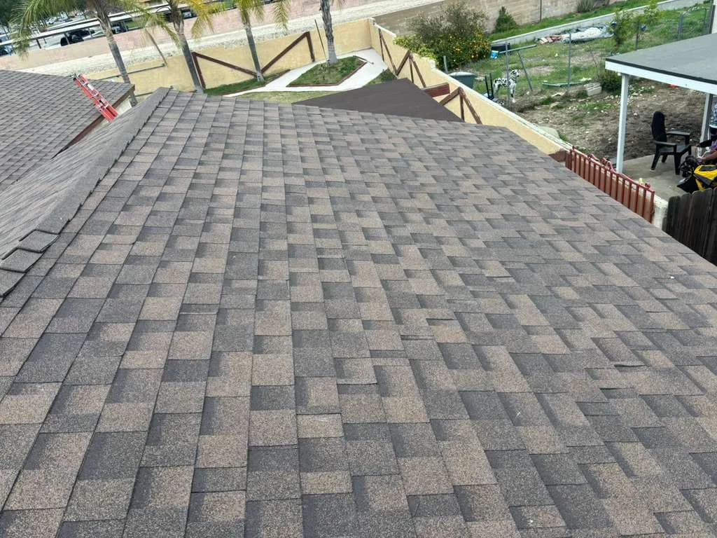 Dimensional asphalt shingles covering connected roof slopes with ridge detailing