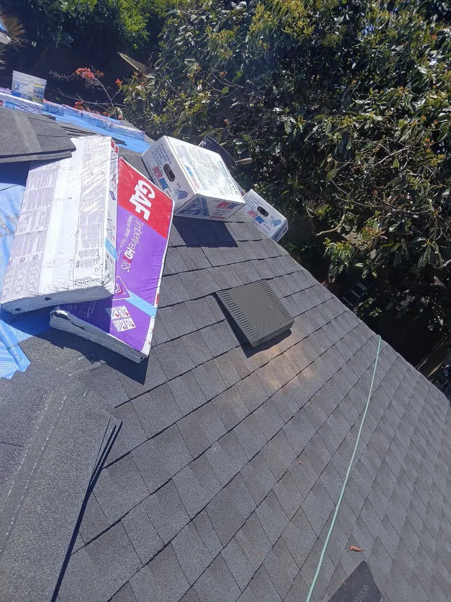 Packaged roofing materials resting on a dark shingle roof