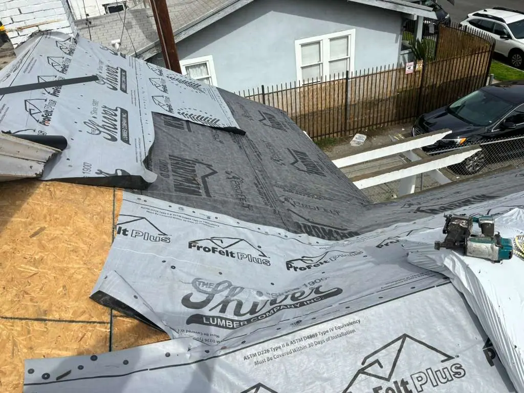Printed underlayment across a roof slope beside an exterior wall and vent pipe