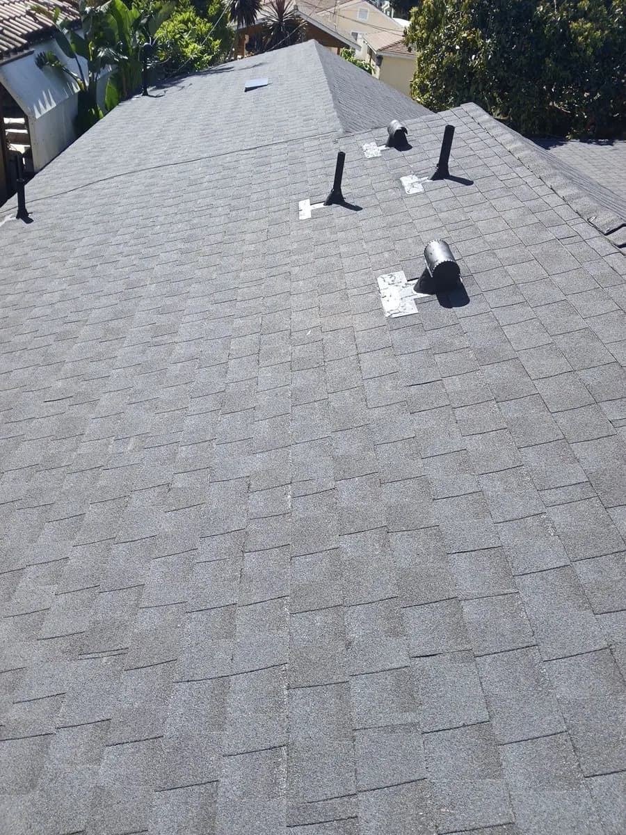 Gray shingle hip roof with multiple vent penetrations