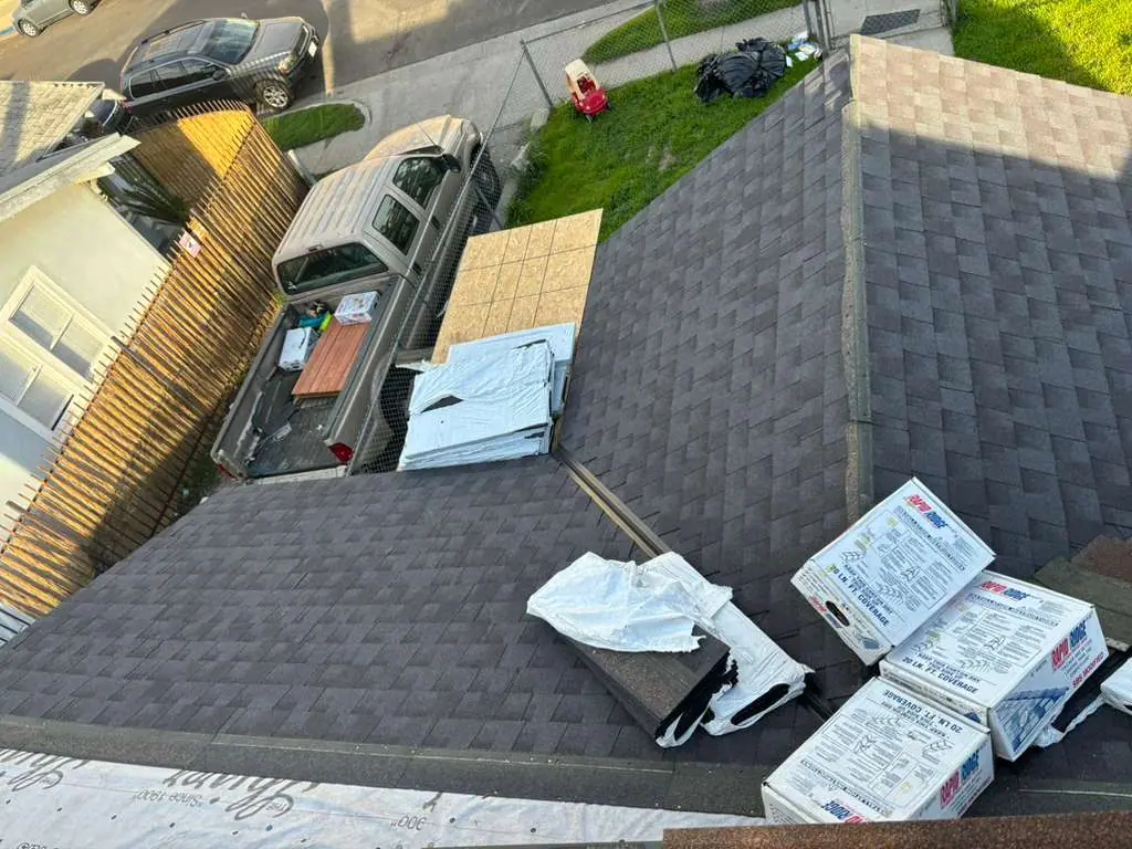 Shingle roof planes with packaged materials near a roof intersection