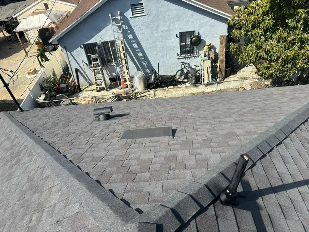 Shingle roof valley beside an exterior facade and roof penetrations