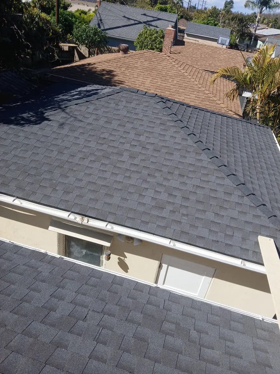 Dark shingle roof with a separate brown roof slope behind it