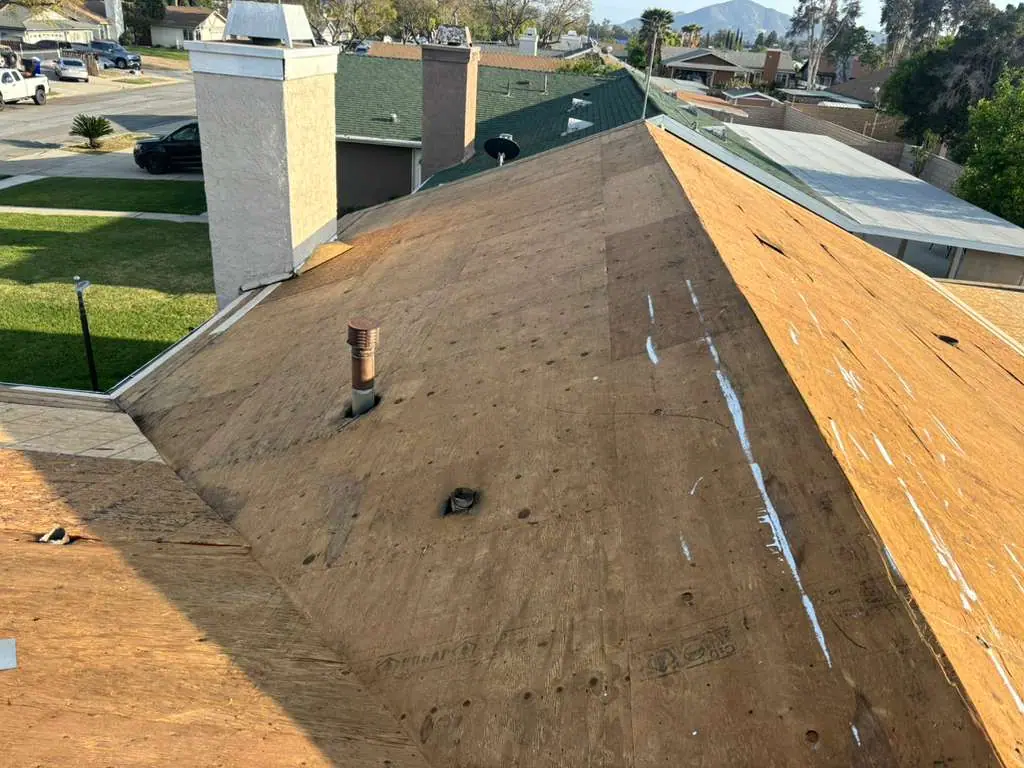 Exposed wood roof decking beside a light chimney and underlayment